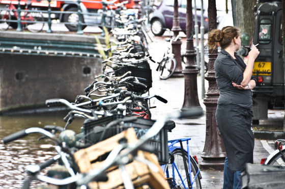 woman smoking with row of bikes