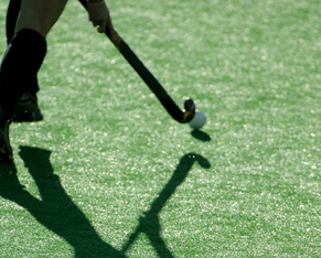 The shadow of a field hockey player as they run down the pitch.