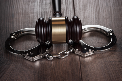 handcuffs and judge gavel on brown wooden table