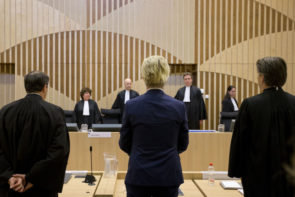 Geert Wilders rises as judges enter the court room for a pretrial hearing at a high-security court. Photo: AP Photo/Peter Dejong