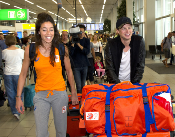 Speed skating champ Sven Kramer helps hockey player girlfriend Naomi van As with her bags at Schiphol. Photo: VI Images