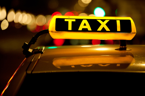 Taxi cab sign on top of the vehicle at nighttime