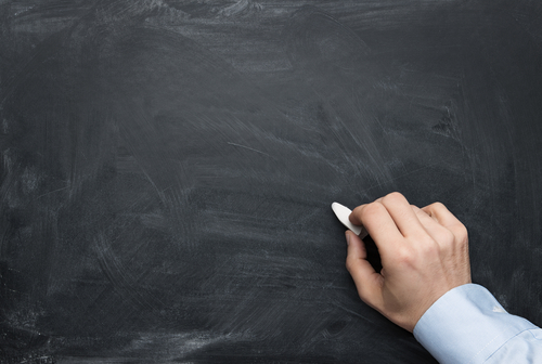 Close up of male hand writing on a blackboard with copy space fo