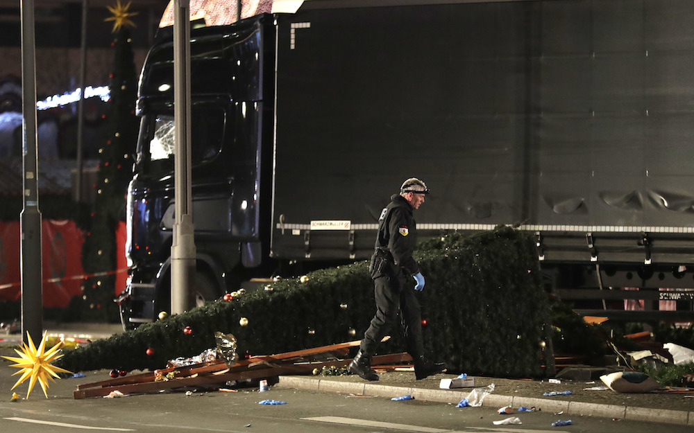A police officer investigate the scene after a truck ran into a crowded Christmas market and killed several people in Berlin. Photo: AP Photo/Michael Sohn via HH