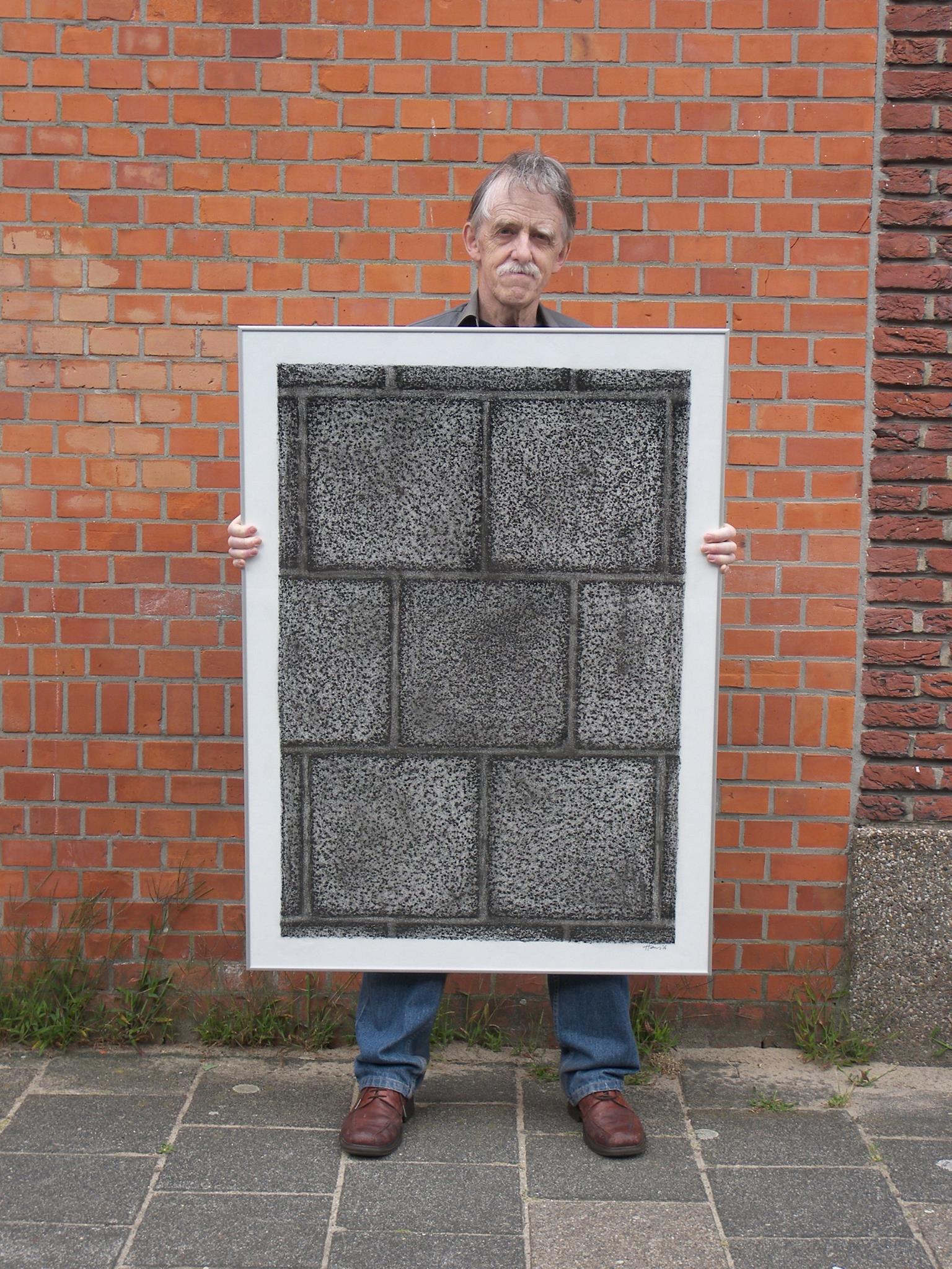 Hans Rietbergen holding up a rubbing of the paving stones where he takes pictures of people passing by his home.