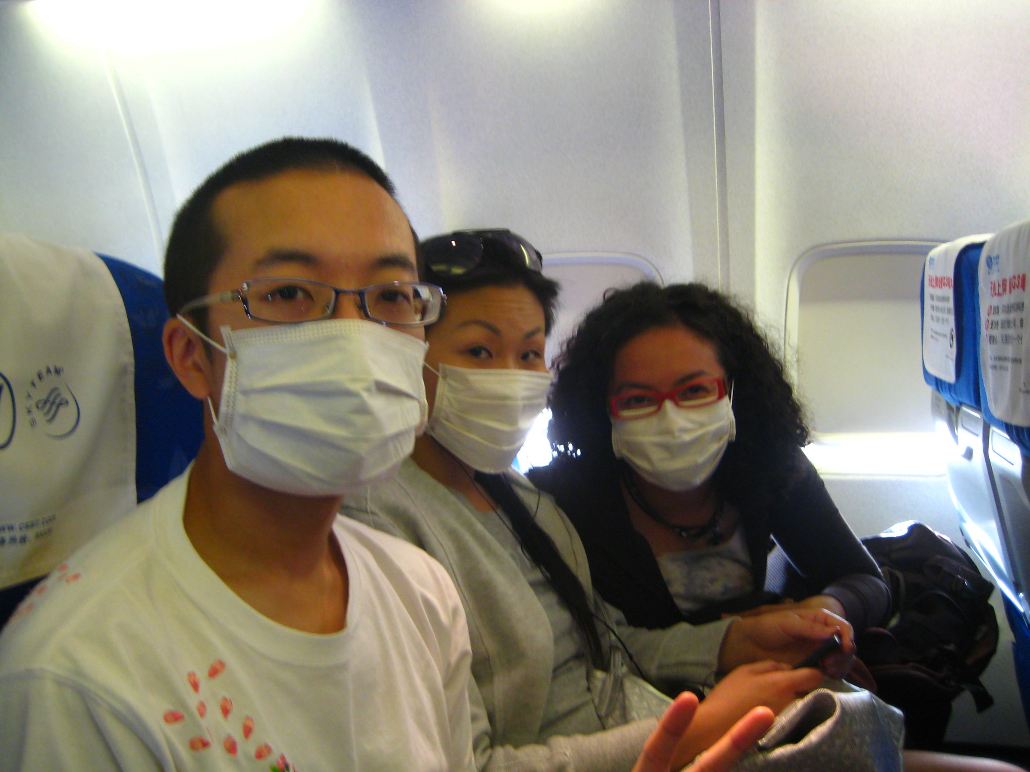 Three people in an aeroplane wearing facemasks