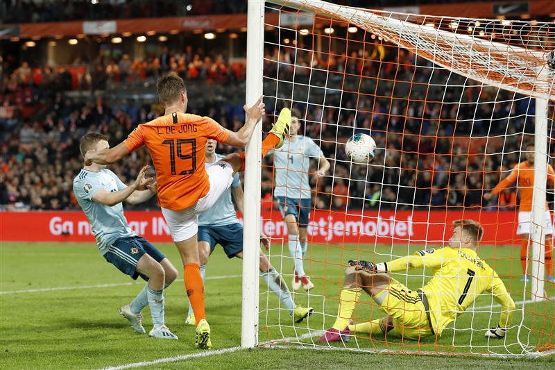 Luuk de Jong holding onto the post while scoring the decisive second goal for the Netherlands against Northern Ireland.