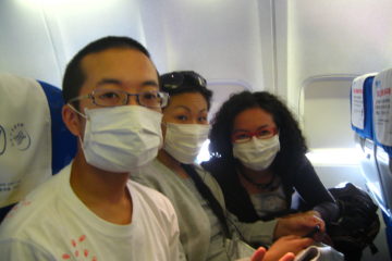Three people in an aeroplane wearing facemasks
