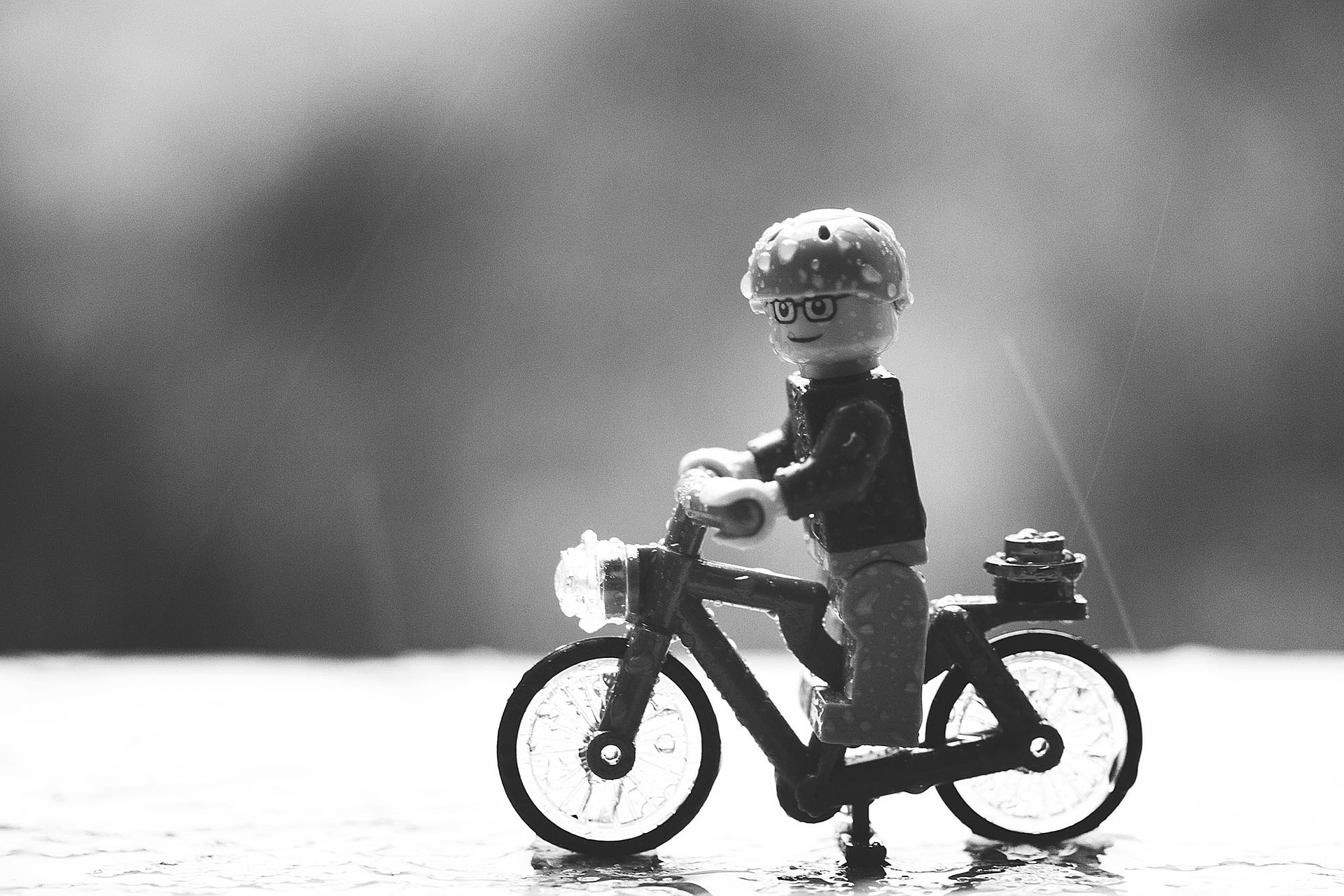 Black and white image of Lego figure on miniature bicycle