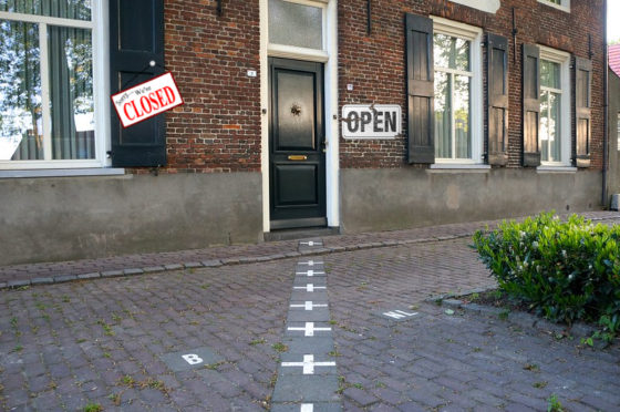 Photomontage of a house in Baarle-Nassau with a shop closed sign on the Belgian side and an open sign on the Dutch side