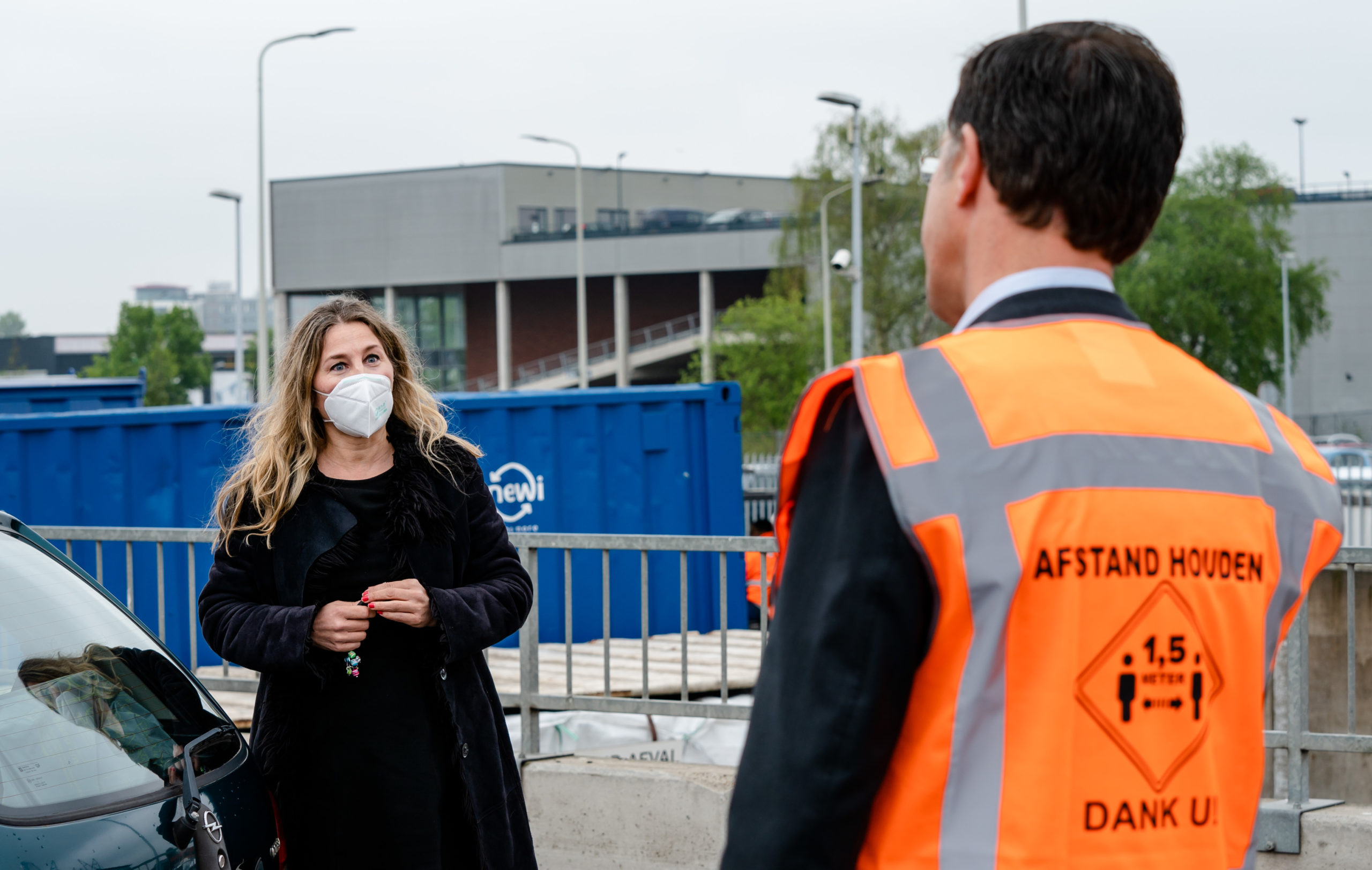 Mark Rutte speaking to a woman wearing a face mask during a site visit to The Hague's refuse collection service.