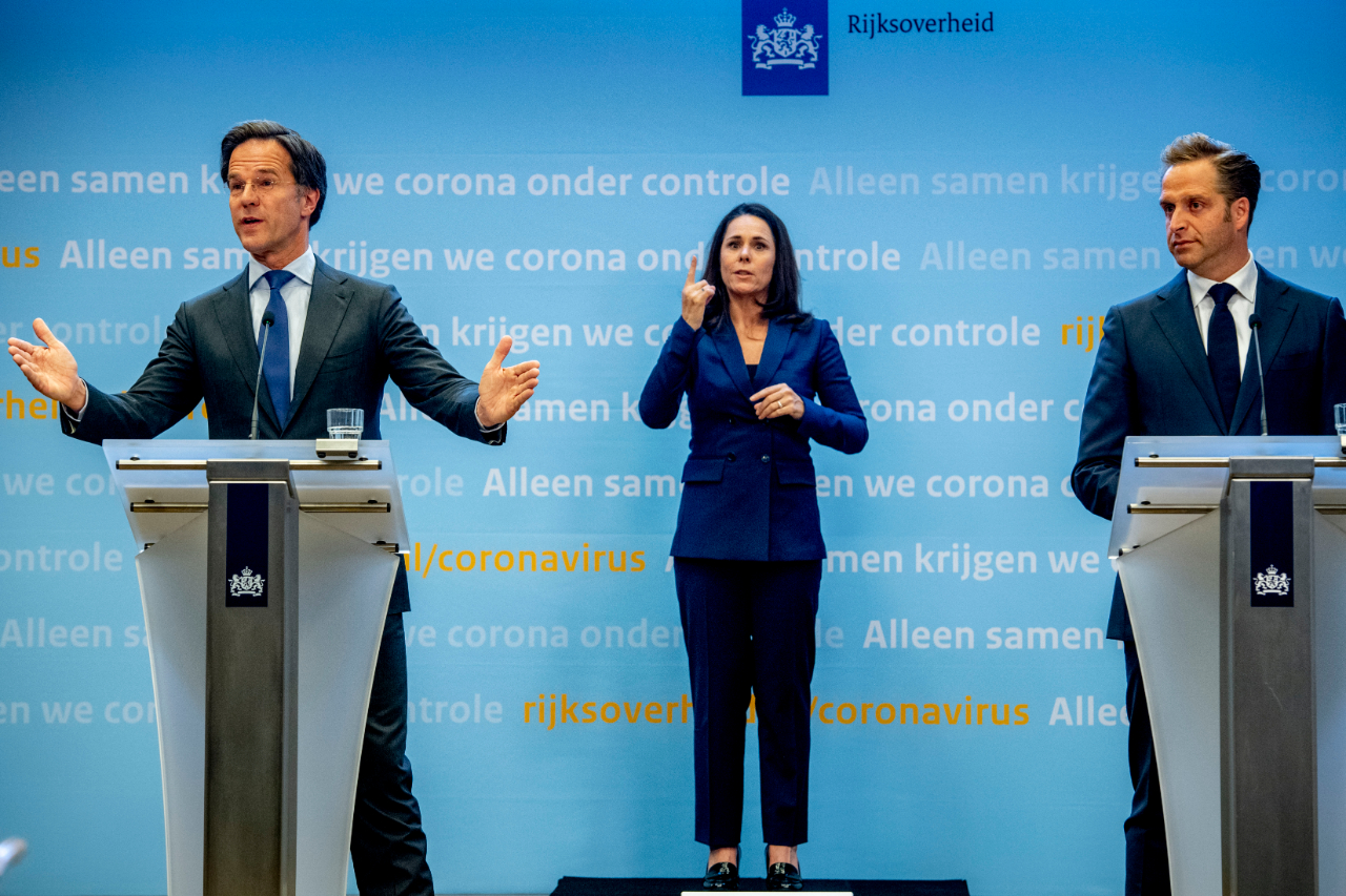 Mark Rutte, sign language interpreter Irma Sluis and health minister Hugo de Jonge on stage at a press conference
