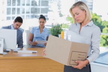 一名妇女从办公室的办公桌上搬走一箱物品