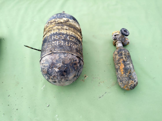 An oxygen cylinder from the wreckage laid out on a green tablecloth.