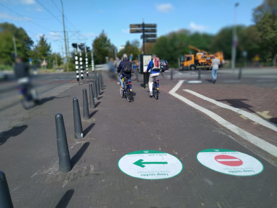 A green direction sticker and red 'no entry' sticker on the ground to indicate the one-way system near The Hague Central Station