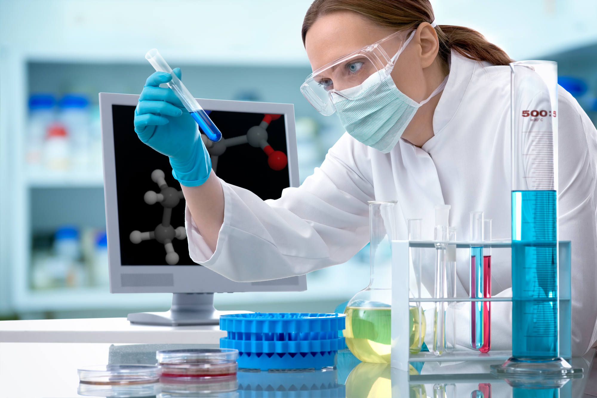 A woman in a testing laboratory studying a sample in a test tube