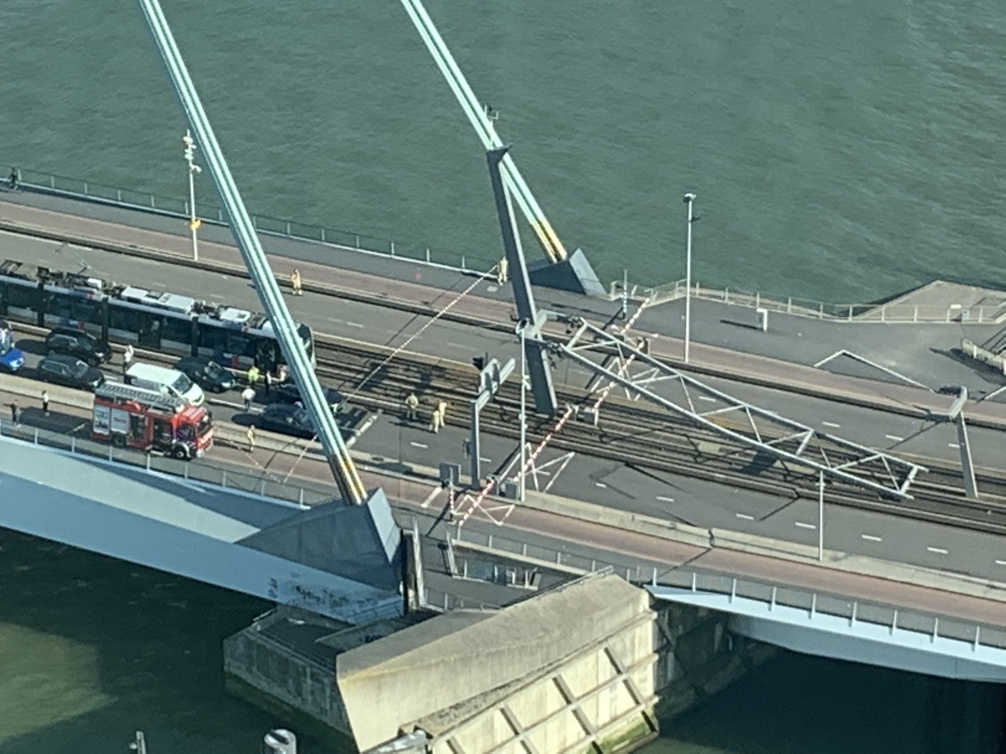 An overhead view of the bridge with the cable support lying on the ground at one end.