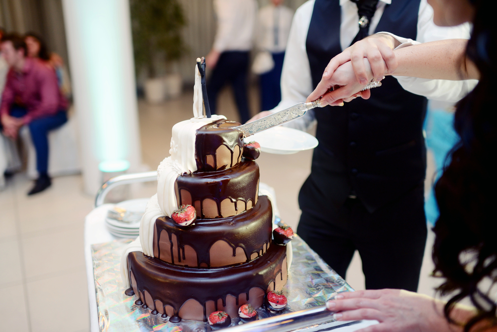 a close-up of a wedding cake coated in chocolate being sliced