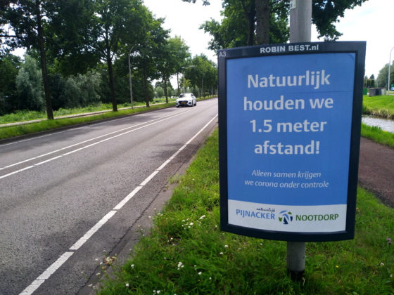A roadside poster with the slogan Natuurlijk houden we 1.5 meter afstand! to remind people of the coronavirus social distancing rules.