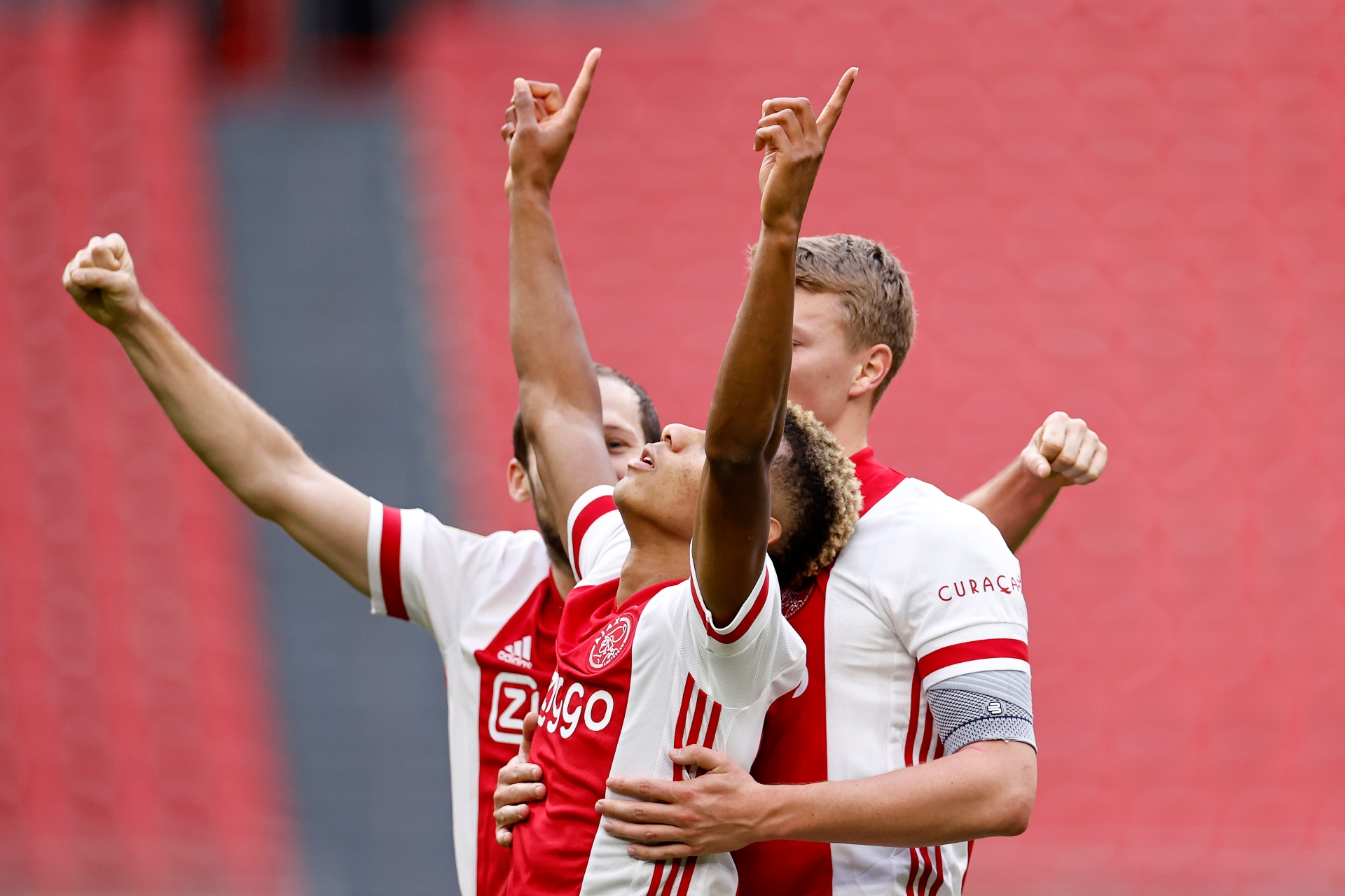 Ajax winger David Neres raises his arms as he celebrates scoring Ajax's second goal with team-mates Daley Blind and Per Schuurs.