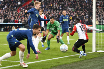 PSV Eindhoven goalkeeper Walter Benitez clutching the ball as Feyenoord players surround his goal.